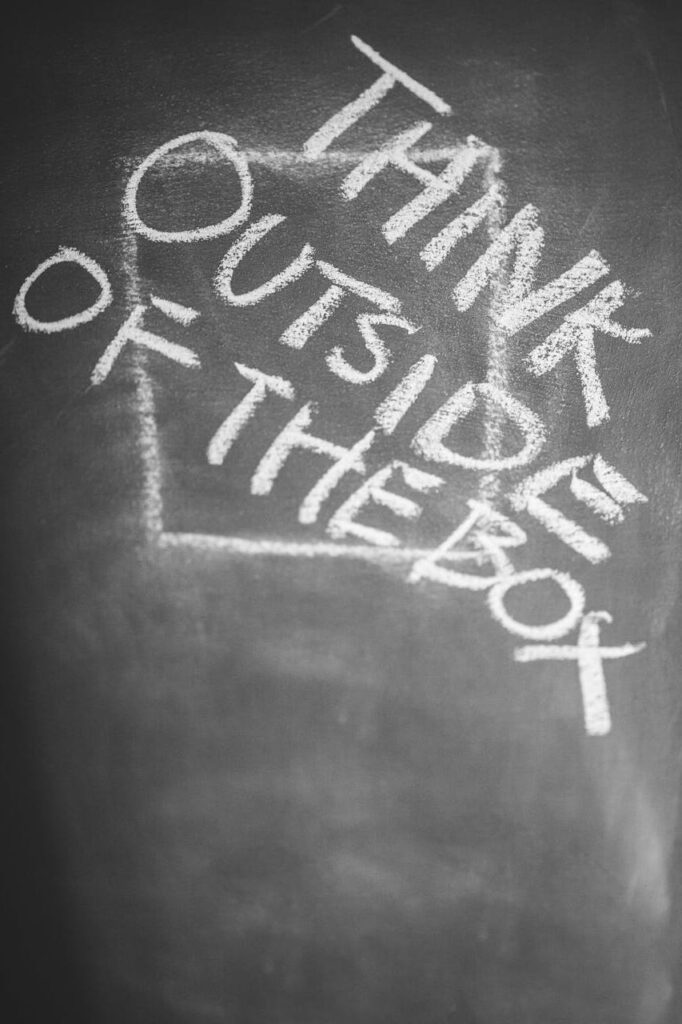 Chalkboard with 'Think Outside the Box' handwritten, inspiring creativity.